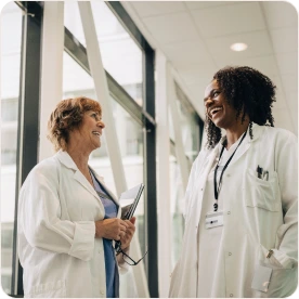 Two female doctors are laughing together in a hallway