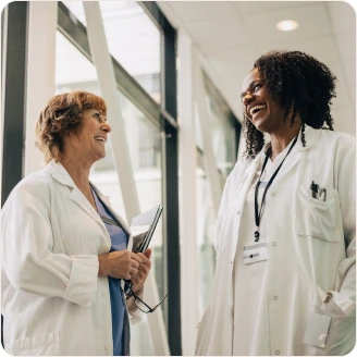 Two female doctors are laughing together in a hallway